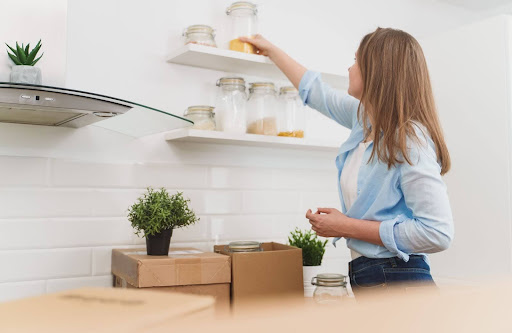 Woman take items off from the shelf in the kitchen